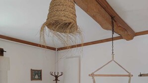 A room with a bed, a small table, a lamp, and a hanging basket. - Chambre D'hôte à La Cour Souveraine Près des Plages du Débarquement et de Bayeux (Mosles)