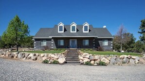 A two-story house with a stone facade, a dark blue front door, and a satellite dish on the roof.