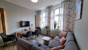Una sala moderna con un sofá gris, una mesa de comedor de madera y sillas negras.
