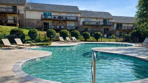Una piscina con sillones de descanso y un edificio de piedra al fondo.