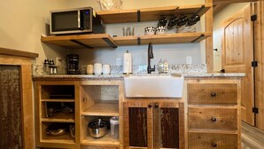 A kitchen with wooden cabinetry, a microwave, a coffee maker, and a sink.