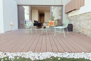 Een houten terras met twee stoelen, een tafel en een bloempot.