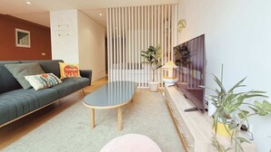 Una sala de estar moderna con un sofá, una mesa de centro, un televisor y una planta.