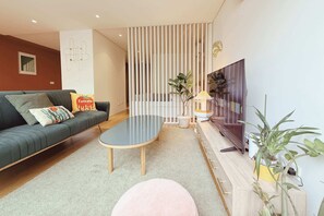 Een moderne woonkamer met een bank, een salontafel, een televisie en een plant.