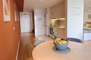 Een moderne keuken met een marmeren spatwand, een eethoek met een ronde tafel, en een fruitschaal.