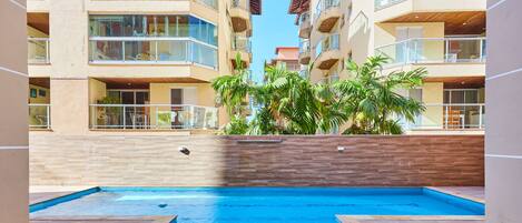 Una piscina al aire libre, sombrillas, sillones reclinables de piscina