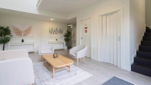 A modern lobby with a reception desk, white sofas, a coffee table, and a staircase. - Charming Restful Flat w/ Terrace by HostWise (Porto)