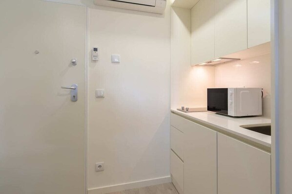 Une cuisine moderne avec des meubles blancs, un four à micro-ondes et un évier.