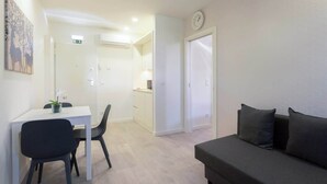 A modern living room with a sofa, a dining table with chairs, and a kitchen area in the background. - Charming Restful Flat w/ Terrace by HostWise (Porto)