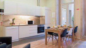 A modern kitchen with white cabinets, a microwave, and a dining area with a table set for four.