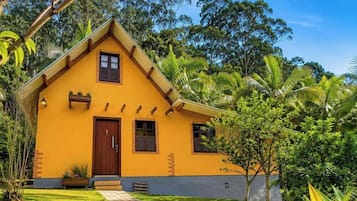 Una casa amarilla con puerta marrón, ventanas y un pequeño porche.