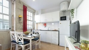 A compact kitchen with white cabinets, a microwave, a sink, and a television.