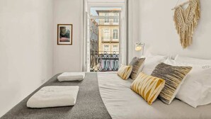 A bedroom with a bed, pillows, a macrame wall hanging, and a framed picture.