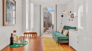 A compact living space with a dining area, a sofa, and a view of the street through a glass door.