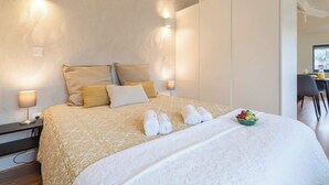 Habitación de hotel moderna con una cama grande, lámparas de noche y un frutero sobre la cama.
