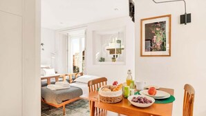Una habitación acogedora con una cama, una mesa de comedor con alimentos para el desayuno y un cuadro en la pared.