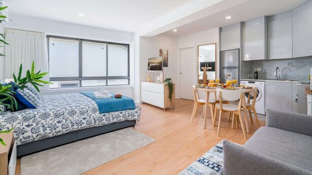 Un appartement moderne comprenant un lit, un coin repas et une cuisine.