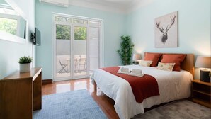A bedroom with a bed, a bedside table, a nightstand, a window, and a door leading to a balcony.