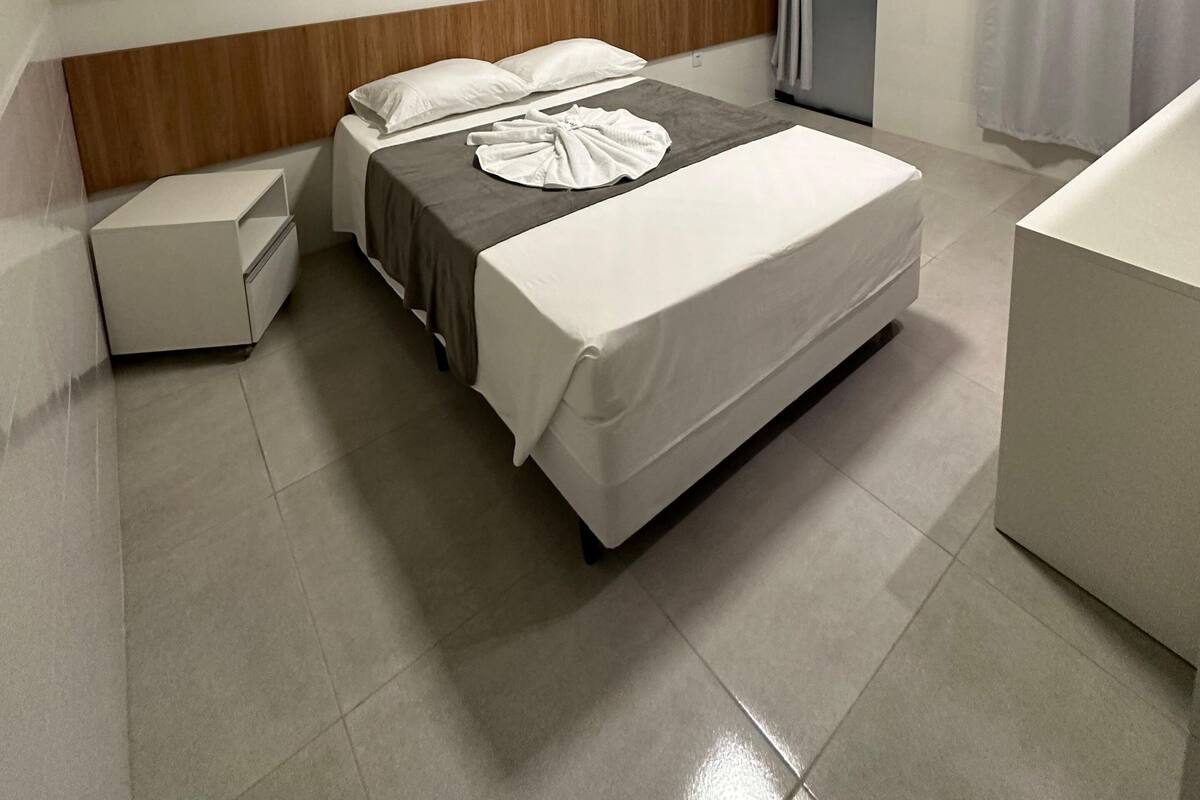 Ein Hotelzimmer mit Bett, Nachttisch, Bad mit Badewanne und einer Tür.