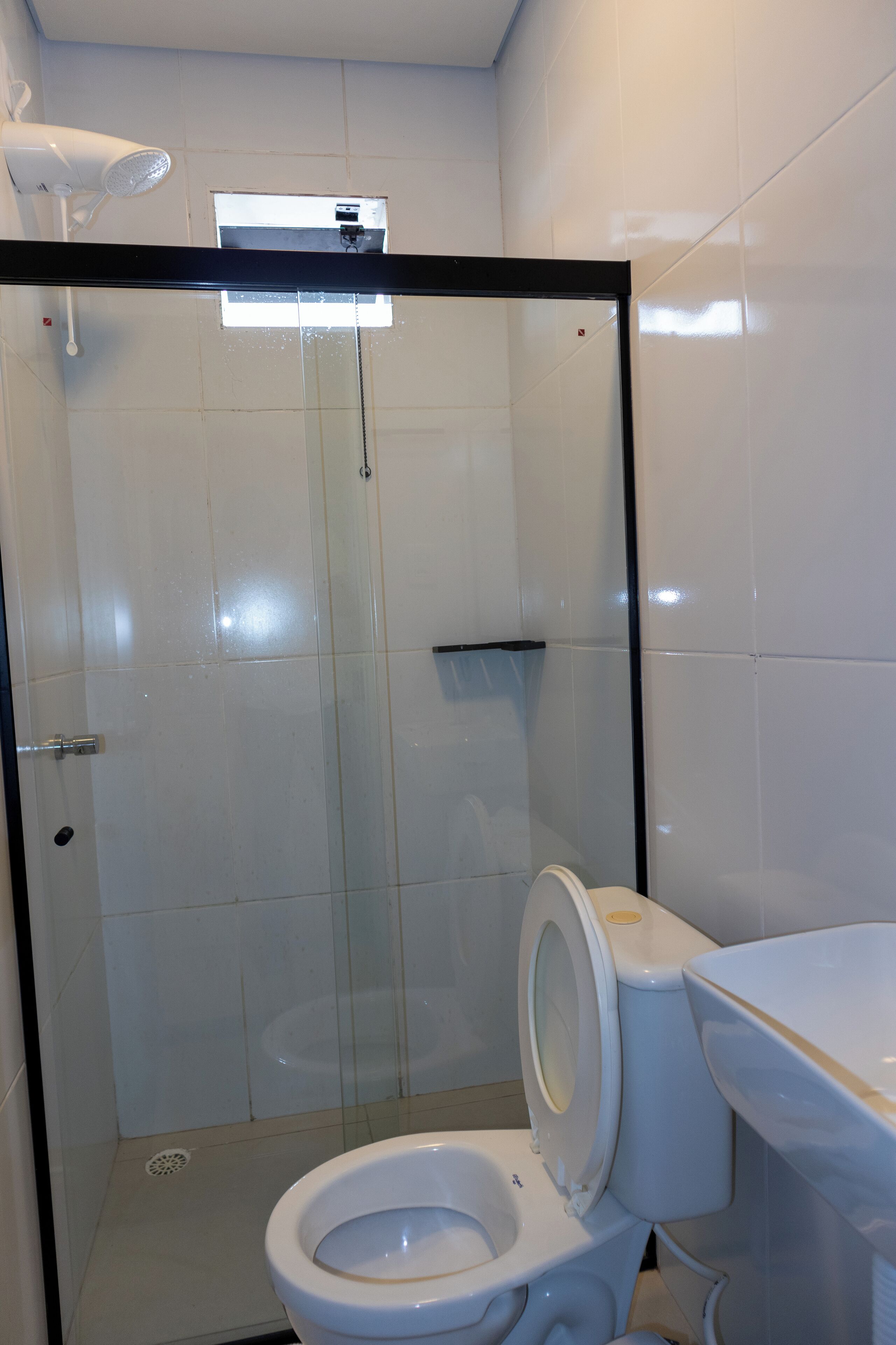 A bathroom with a glass-enclosed shower, a toilet, and a sink.