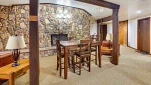 A dining area with a stone wall, wooden furniture, and a fireplace. - Cozy Condo w/ Fireplace - Near Brian Head Resort! (Brian Head)
