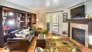 A living room with a fireplace, a television, and a bookshelf. - Cozy Condo w/ Fireplace - Near Brian Head Resort! (Brian Head)