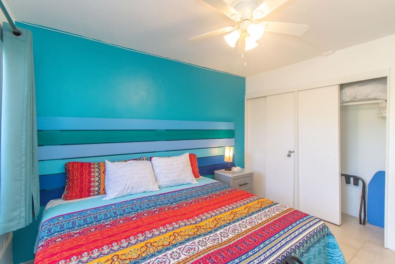 A bedroom with a bed, a nightstand, a ceiling fan, and a wardrobe.