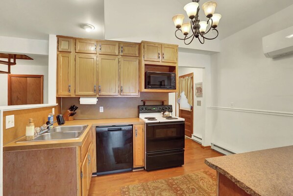 A compact kitchen with wooden cabinets, a built-in microwave, a stove, and a dishwasher. - Raystown Retreat- Snyders Run, Aunt Susie's (Huntingdon)