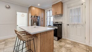 A kitchen with a central island, wooden cabinets, stainless steel appliances, and a white door. - Le Patrimonial-Two bedrooms 6 persons (Québec City)