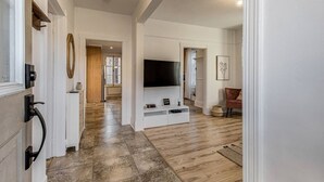 A spacious living room with a large TV, wooden flooring, and a cozy seating area. - Le Patrimonial-Two bedrooms 6 persons (Québec City)