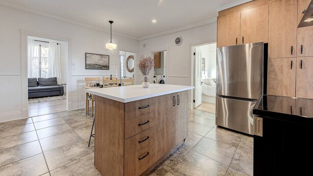 A modern kitchen with a central island, stainless steel appliances, and a dining area with a sofa and table. - Le Patrimonial-Two bedrooms 6 persons (Québec City)
