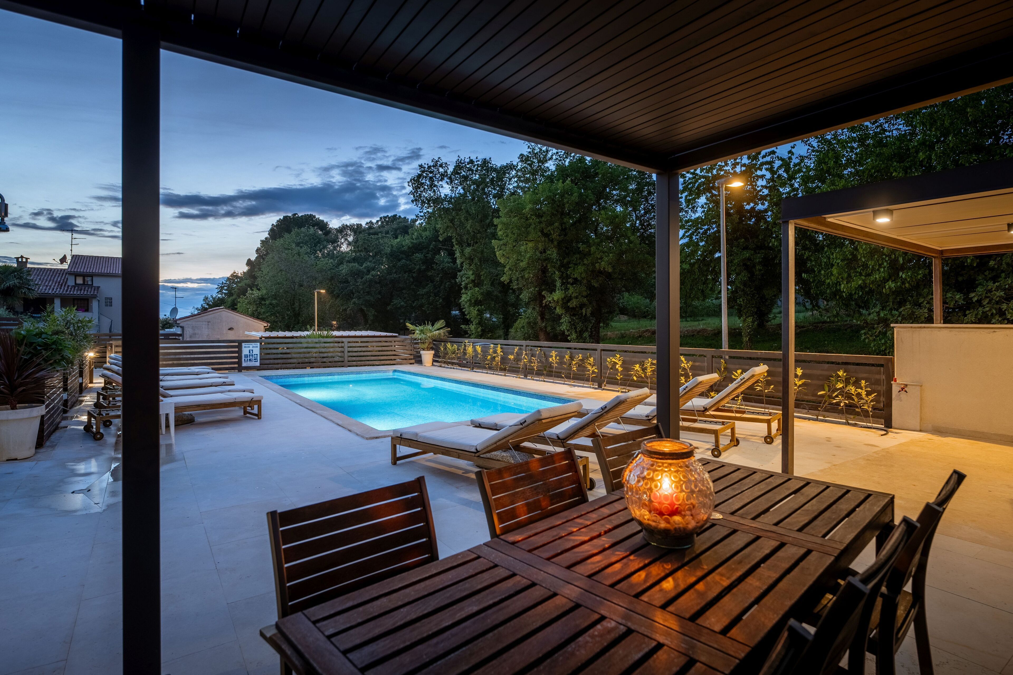Un espace extérieur abrité comprenant une piscine, des chaises longues et une table avec une bougie.