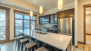 Una cocina moderna con una isla grande, electrodomésticos de acero inoxidable y taburetes de bar.