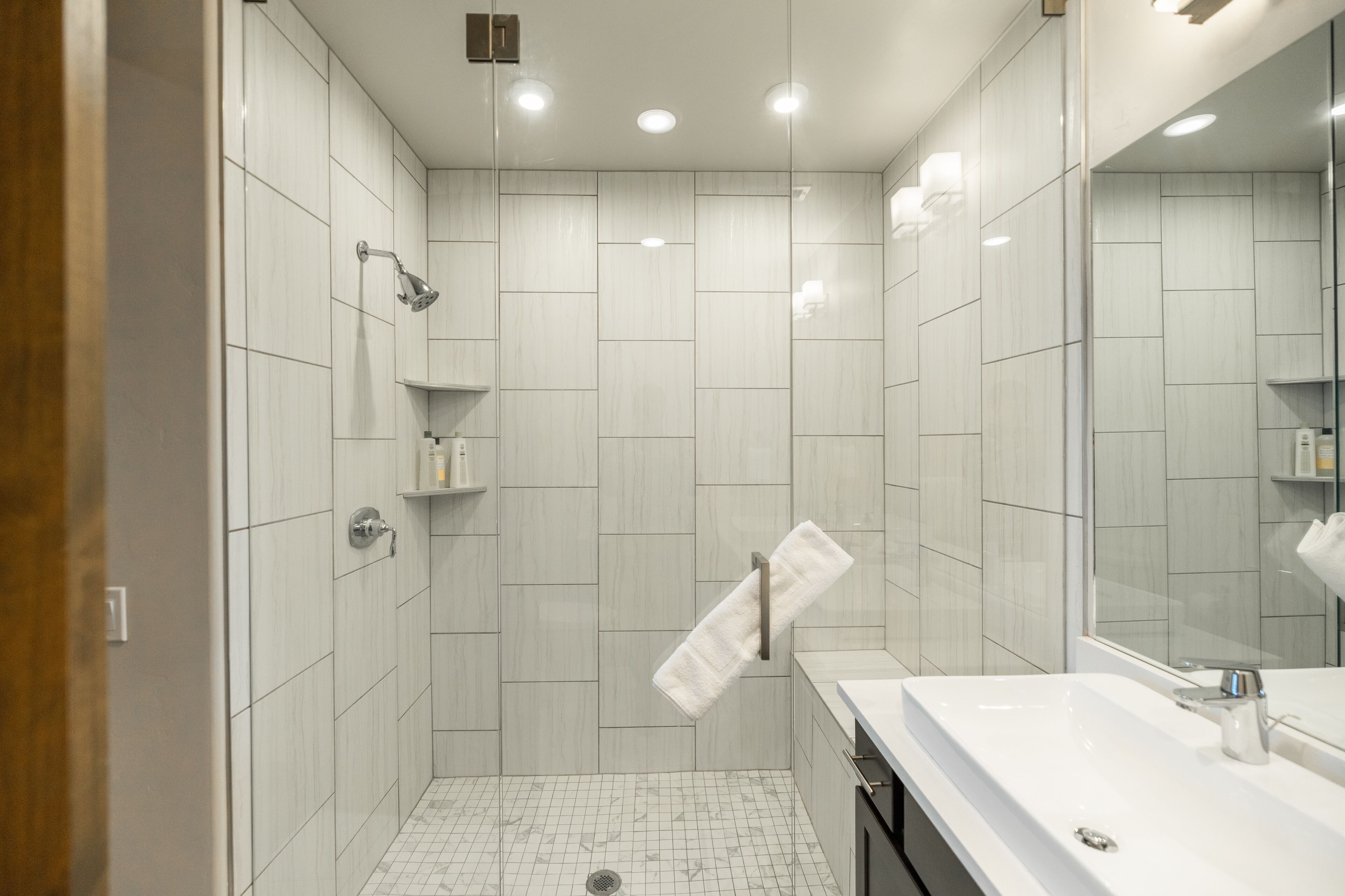 A modern bathroom with a shower, a sink, and a mirror.