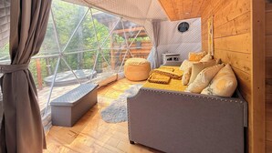 Ein gemütlicher, geometrisch gestalteter Raum mit großem Fenster, Holzwänden und einer komfortablen Sitzecke.