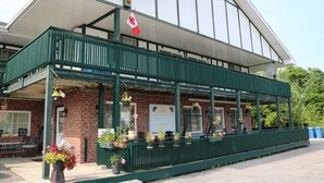 Un edificio con un área de estar al aire libre techada, fachada de ladrillo y una bandera canadiense.