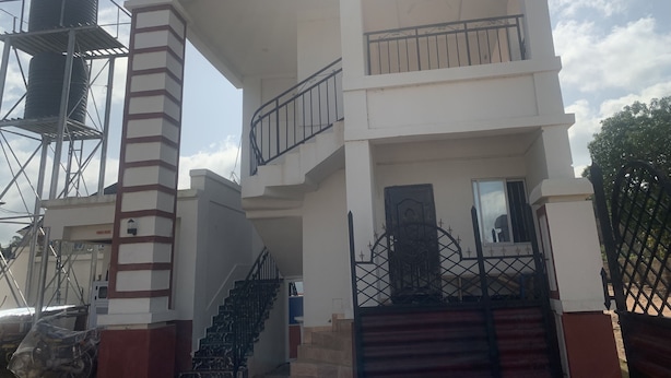 Un edificio de varios pisos con una escalera, un balcón y una entrada protegida por una reja.