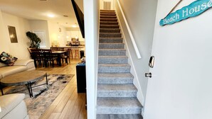 Een trap die leidt naar een tweede verdieping, met een bord waarop staat 'Beach House'.