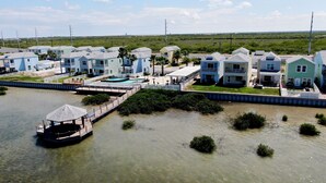 Een pand aan het water met meerdere tweelaagse huizen, een steiger en een klein bootje.