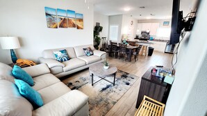 Een moderne woonkamer met een bank, salontafel en een eetgedeelte met stoelen en een tafel.