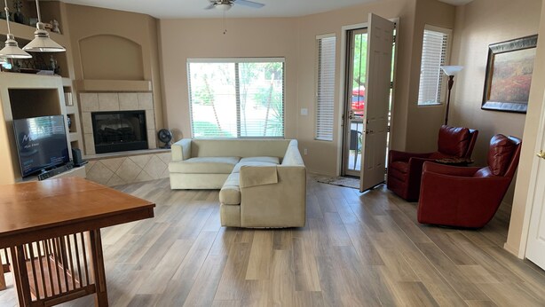 A spacious living room with a large sofa, a wooden dining table, and a fireplace. - Special Summer Rates 1-6 Months Begin April Near Restaurant & Shopping (Fountain Hills)