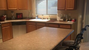 A kitchen with wooden cabinets, a central island, a dishwasher, and a window with blinds. - Special Summer Rates 1-6 Months Begin April Near Restaurant & Shopping (Fountain Hills)