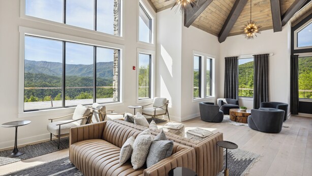 Amplia habitación con ventanas grandes, techo de madera y muebles modernos.