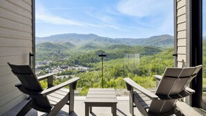 Un balcón con dos sillas y una mesa, con vistas a un paisaje montañoso.