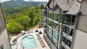 Ein modernes Hotel mit Pool, Liegestühlen und Blick auf den umliegenden Wald.