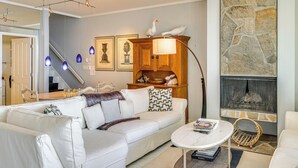 Una sala moderna con un sofá blanco, una mesa de centro, una chimenea y una pared de acento de piedra.