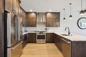 A modern kitchen with wooden cabinets, stainless steel appliances, and pendant lighting. - 3 BD| Pool & Mountain View| Sleeps 8| Luxury Condo| $1000 Free Tickets (Gatlinburg)
