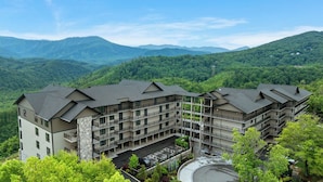 Ein mehrstöckiges Hotel mit Innenhof, umgeben von üppiger Vegetation und Bergen im Hintergrund.