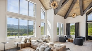 A spacious room with large windows, a high ceiling, and a view of mountains.