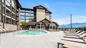A hotel with a pool, lounge chairs, and a mountain view. - Stylish Modern 3 BR Condo + Views (Gatlinburg)